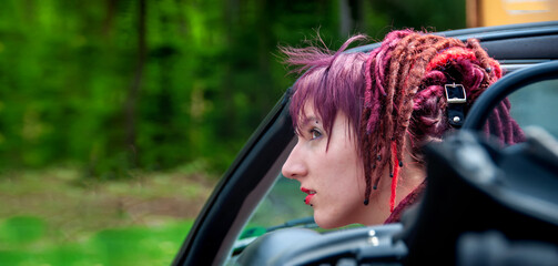 portrait of a fascinating extraordinary extravagant punk woman with pink, violet, red, dreadlocks...
