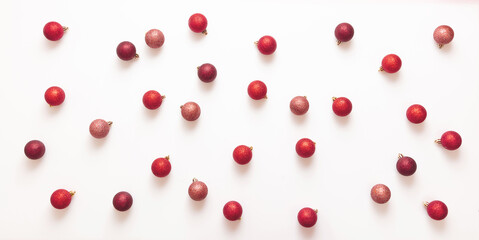 Xmas red shades balls flat lay on white background. Small baubles scattered on card top view.