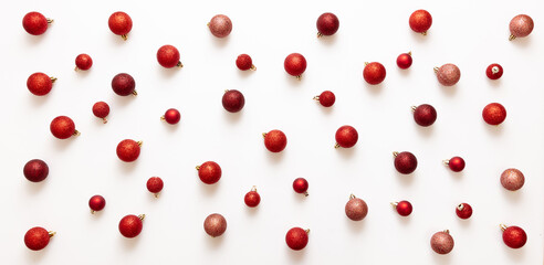 Xmas red shades balls flat lay on white background. Small baubles scattered on card top view.