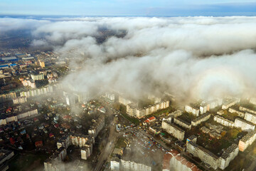 Top aerial view of fluffy white clouds over modern city with high rise buildings.