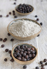Bowls of black chickpea flour and wooden spoon of beans closeup