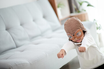 A cute little girl dressed in a cap and glasses of a pilot. The child dreams of becoming a pilot.