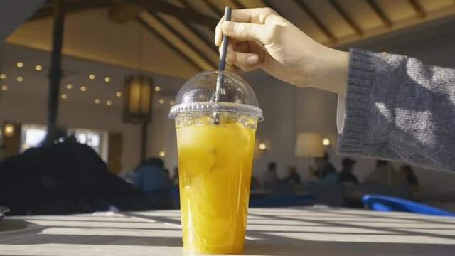 4k, full shot, He's stirring the ade on the cafe table with a straw