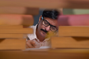 Portrait of an adult man through books taking notes