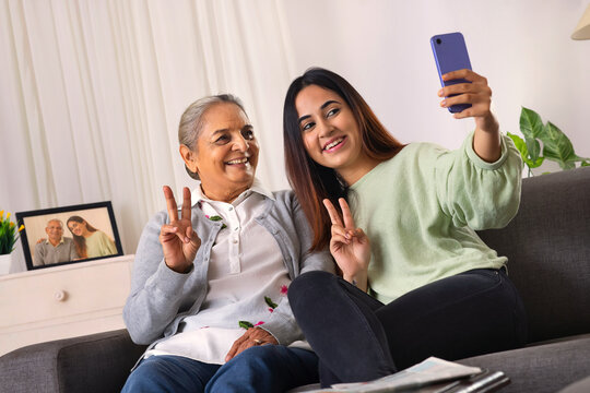 Grandmother and granddaughter taking selfie together at home