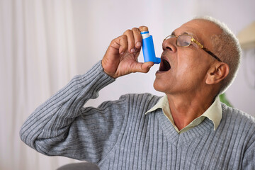 Old age man using her Asthma Inhaler at home - obrazy, fototapety, plakaty