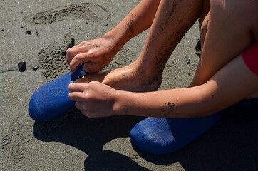 Close up of the child putting on his marine shoes (water shoes, beach shoes). Footwear for water activities.
Good summer vacation.