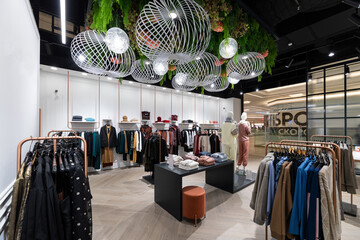 Photo of a store of youth, fashionable and stylish clothes with jeans, outerwear, jacket, shirts, sweater, t-shirt, hoodie, pants, for men and women in a shopping center. Outfit on a mannequin
