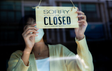a woman hanging "Closed" tag hang on door glass at entrance. cafe or store ready to service 