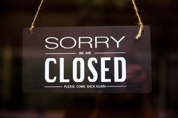 Sorry we are closed wood board hanging on glass door of cafe or store