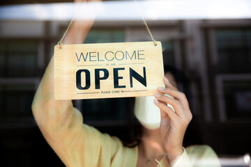 woman hanging an open banner at cafe or restaurant door