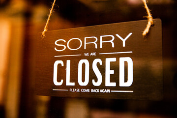 Closed tag, Sorry we are closed sign board hanging on glass door of cafe or store 