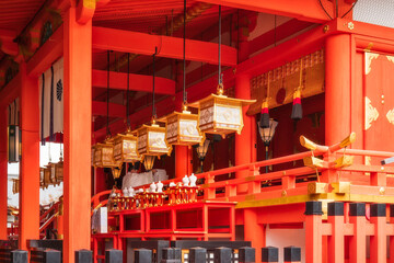 Beautiful architectural detail with the timber structure painted in strong vermillion colours and golden lanterns at one of the buildings of Fushimi Inari Taisha Shinto shrine in Kyoto, Japan.