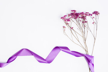 A bouquet of purple flower with purple ribbon over the white background. 