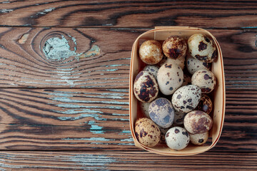 Top view of Quail eggs in wooden box on wooden background. With copy space.