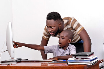 young father teaches his little boy to use a laptop.