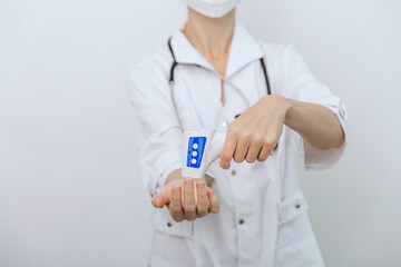 Temperature measurement gun in doctor hands. Close-up shot of doctor wearing protective surgical...