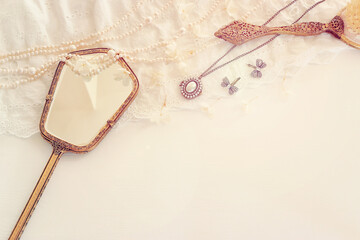 Background of white delicate lace fabric, pearls and vintage hand mirror