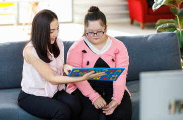 Asian lovely young mother smiling taking care and using alphabet puzzle toy teaching a girl with...