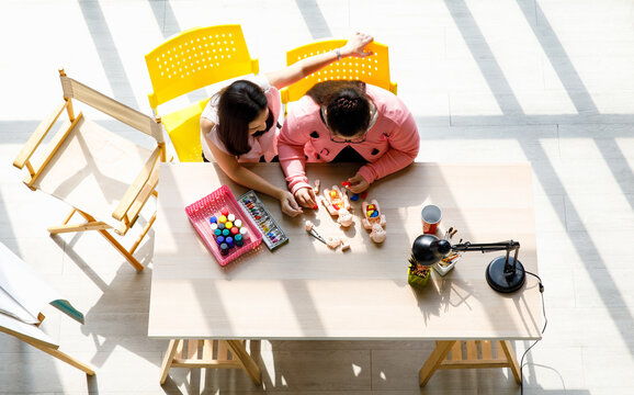 Top view shot of Asian young teacher taking care and using human body anatomy puzzle toy teaching a girl with down syndrome preschooler student kid on table at school