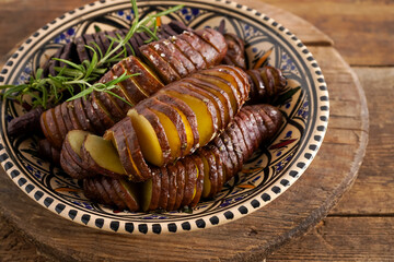 Sweet potato - sweet potatos tubers cooked in a pan. Fried and baked with spices and salt. Cut into pieces and slices. Healthy food close-up top view. Potato meal in a plate on a wooden table. Fork