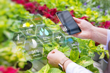 Woman using smart tech for greenhouse plant management - 472178527
