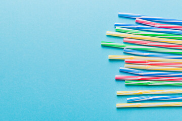 Fototapeta premium Heap of colorful plastic drinking straws on Colored background, flat lay. Copy Space for text