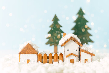 Happy New Year and Merry Christmas postcard. Festive blue background with toy wooden house, snow, light bokeh, christmas tree, village and decoration. Copy space for winter holidays greeting card. 