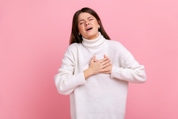 Portrait of young adult sick woman standing and holding hand on his chest and feeling pain heart,...