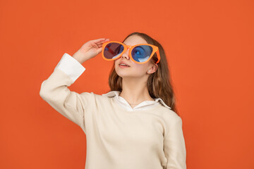 smiling teen girl in party glasses on orange background, glasses