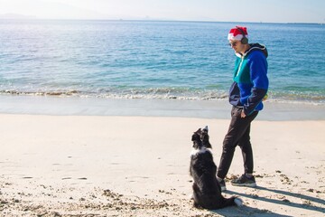 man with dog on the beach playing at christmas time