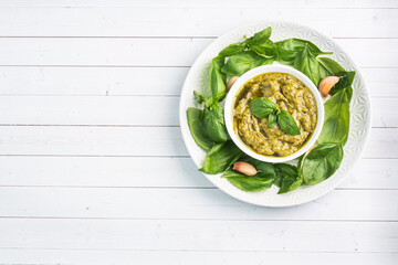 Pesto sauce in a plate and fresh basil leaves with garlic. copy space