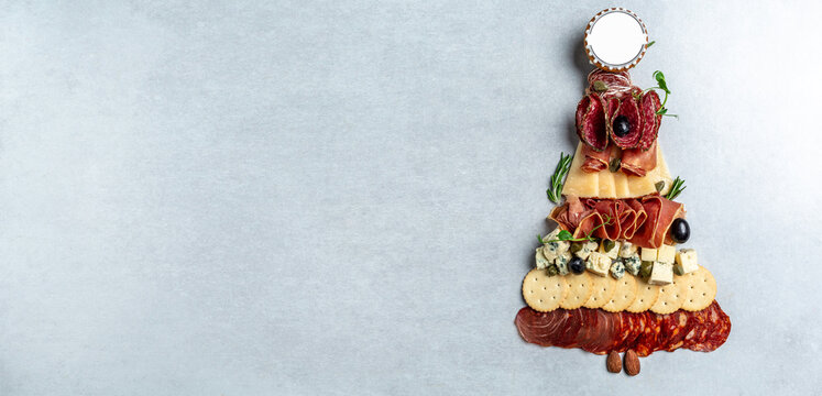 Mixed cheese and meat snacks of Christmas tree. Appetizers or antipasto set with gourmet food. Long banner format. top view