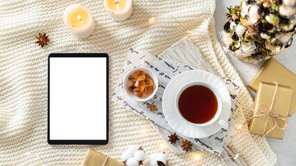 Obraz na płótnie Canvas Cozy Christmas composition with tablet PC, gift boxes, Christmas tree, candles and a cup of tea. Hygge. Flat lay, top view, sample, copy space. Winter on line shopping, christmas sale background