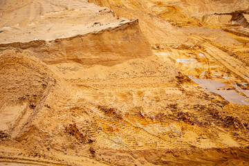Textural sand, with  relief surface, multi-colored layers and different in size of granules, in outdoor sand career, after mining ore and sand for construction.