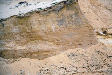Textural sand, with  relief surface, multi-colored layers and different in size of granules, in outdoor sand career, after mining ore and sand for construction.