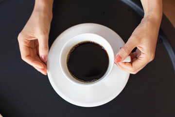 Flat lay of porcelain mug of espresso in hands.