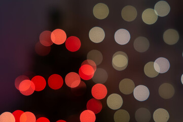 Defocused Christmas tree with glowing lights and ornaments. Interior of room decorated for Christmas and New Year with sparkling garlands, blurred view. Cozy abstract Christmas and New Year concept.