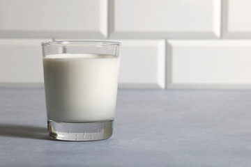 Milk in glass in kitchen on background of tiles on countertop. Closeup copy space.