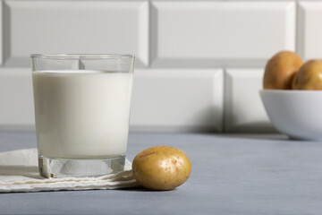 Popapo milk in glass and potatos in kitchen. Alternative vegan milk.