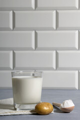 Popapo milk in glass, potato and potato powder in spoon in kitchen. Alternative vegan milk.