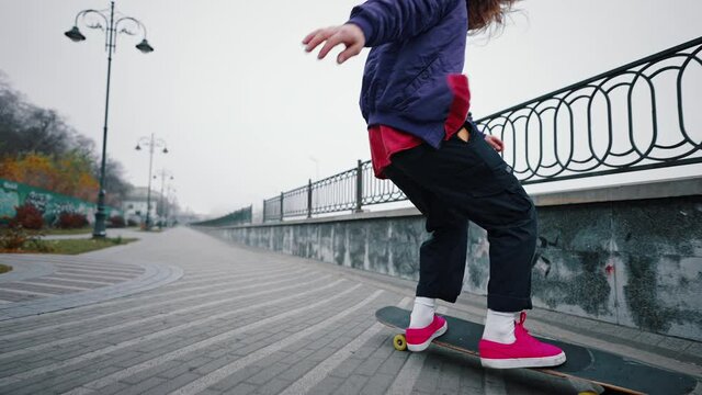 Longhaired young guy demonstrating tricks on a longboard. Urban city street skateboarder skates on sidewalk along the highway, Trendy hipster style leisure transportation