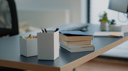 Close up of books and computer with keyboard on desk. Nobody in space for learning and homework with notebooks and pens on table. Empty home office with school supplies