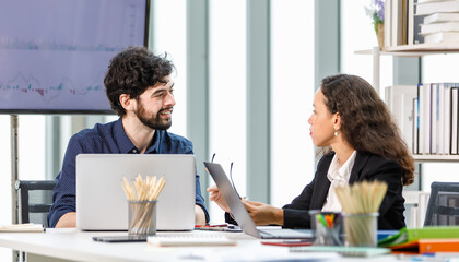 Caucasian bearded businessman trainee working  with African American businesswoman manager trainer in formal suit sitting teaching coaching at working desk