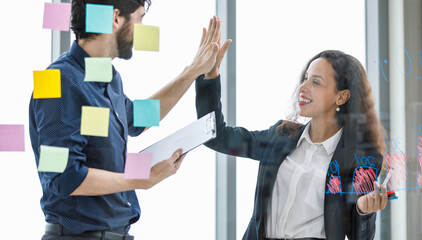 Caucasian bearded businessman holding paper noting board high five with African American...