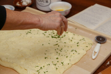 Making of homemade garlic bread. Serie of photos. Butter, cutted parsley and garlic spreaded on sourdough.