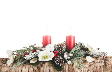Christmas composition made with cork bark, pine, white flowers, red berries, red candles with hot flame, pine cones and snowy branches on white background