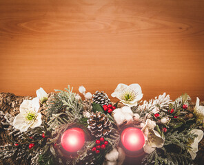 Christmas composition made with cork bark, pine, white flowers, red berries, red candles with hot flame, pine cones and snowy branches on wooden table flat lay view