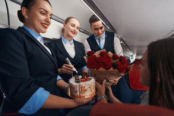 Cheerful cabin crew members handing over presents to female