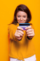 Fototapeta premium Portrait of cheerful woman holding credit card on camera, using card for purchase payment and online shopping with internet banking. Shopaholic person smiling and making money transaction